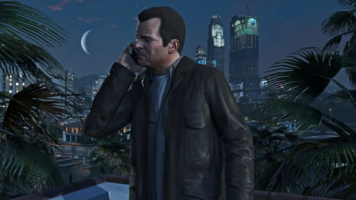 Michael De Santa taking a phone call above the Los Santos skyline at night in GTA V
